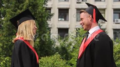 毕业礼服上的金发女郎在领取毕业证书后拥抱最好的朋友